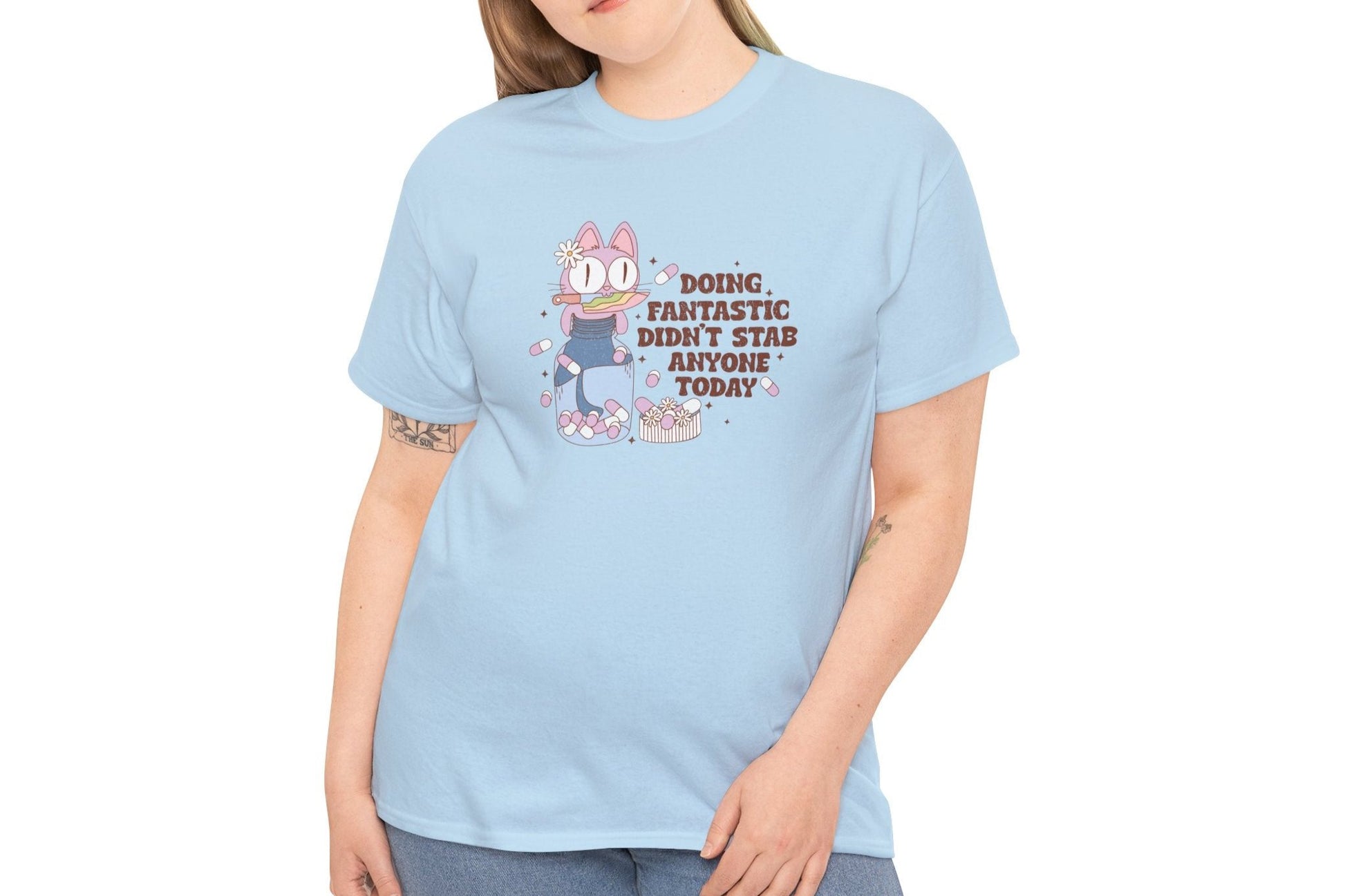 Side view of a model in a light blue T-shirt featuring a cartoon character and the text "Doing Fantastic, Didn't Stab Anyone Today." Part of the Vivid Divergence Sensory Friendly Unisex Tees Range.