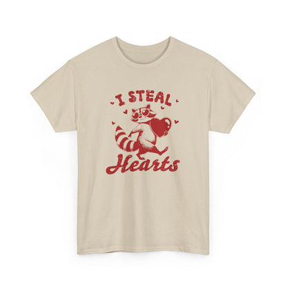 Front view of a beige T-shirt with red text and raccoon illustration holding a heart that reads "I Steal Hearts." Exclusive release for Valentine’s Day. Part of the Vivid Divergence Sensory Friendly Unisex Tees Range.