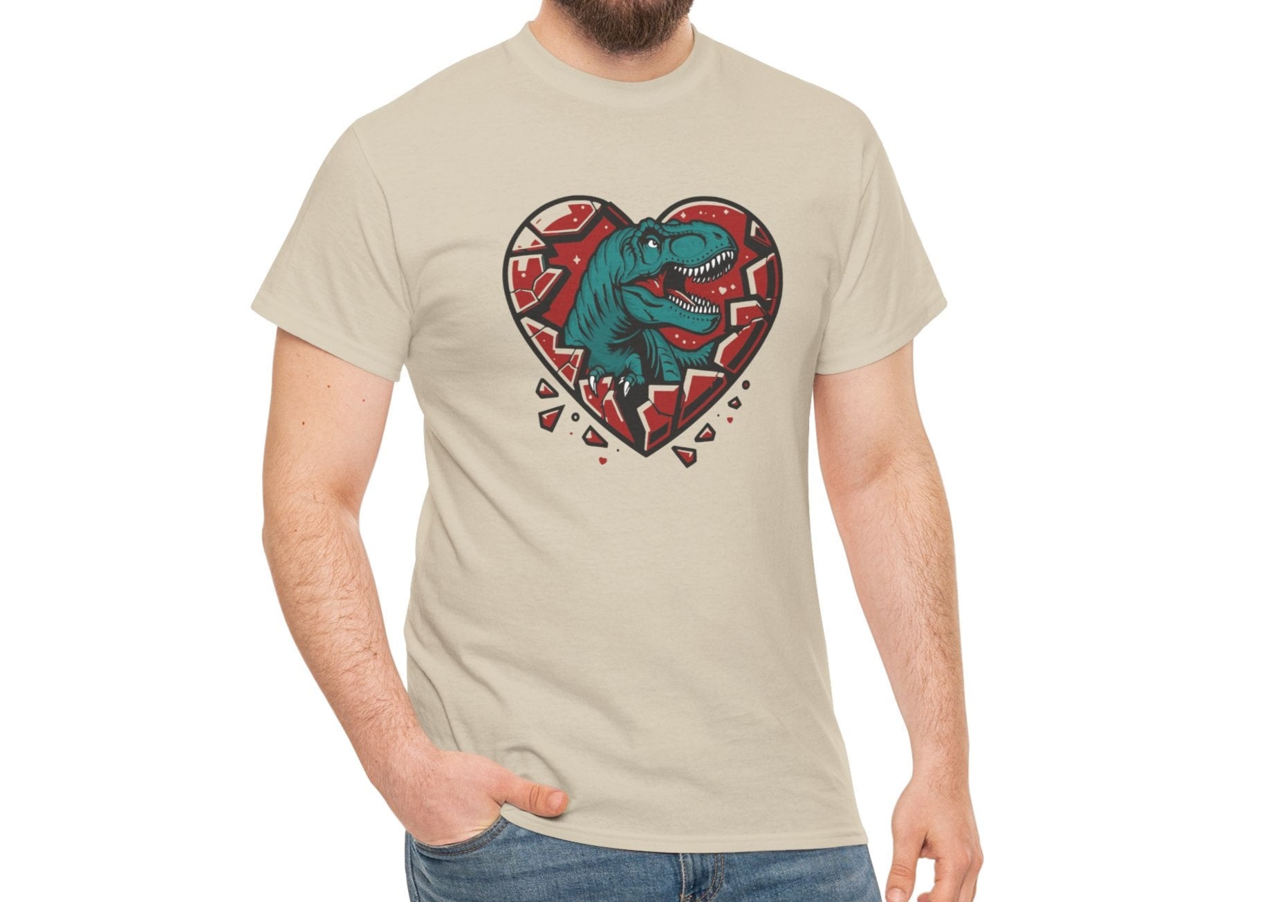 Man wearing a beige T-shirt featuring a green dinosaur inside a cracked red heart with small black hearts around it. Exclusive release for Valentine’s Day. Part of the Vivid Divergence Sensory Friendly Unisex Tees Range.