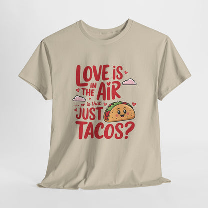 Hanging beige T-shirt featuring red and black text with a taco illustration that reads "Love Is In The Air Or Is It Just Tacos?" Exclusive release for Valentine’s Day. Part of the Vivid Divergence Sensory Friendly Unisex Tees Range.