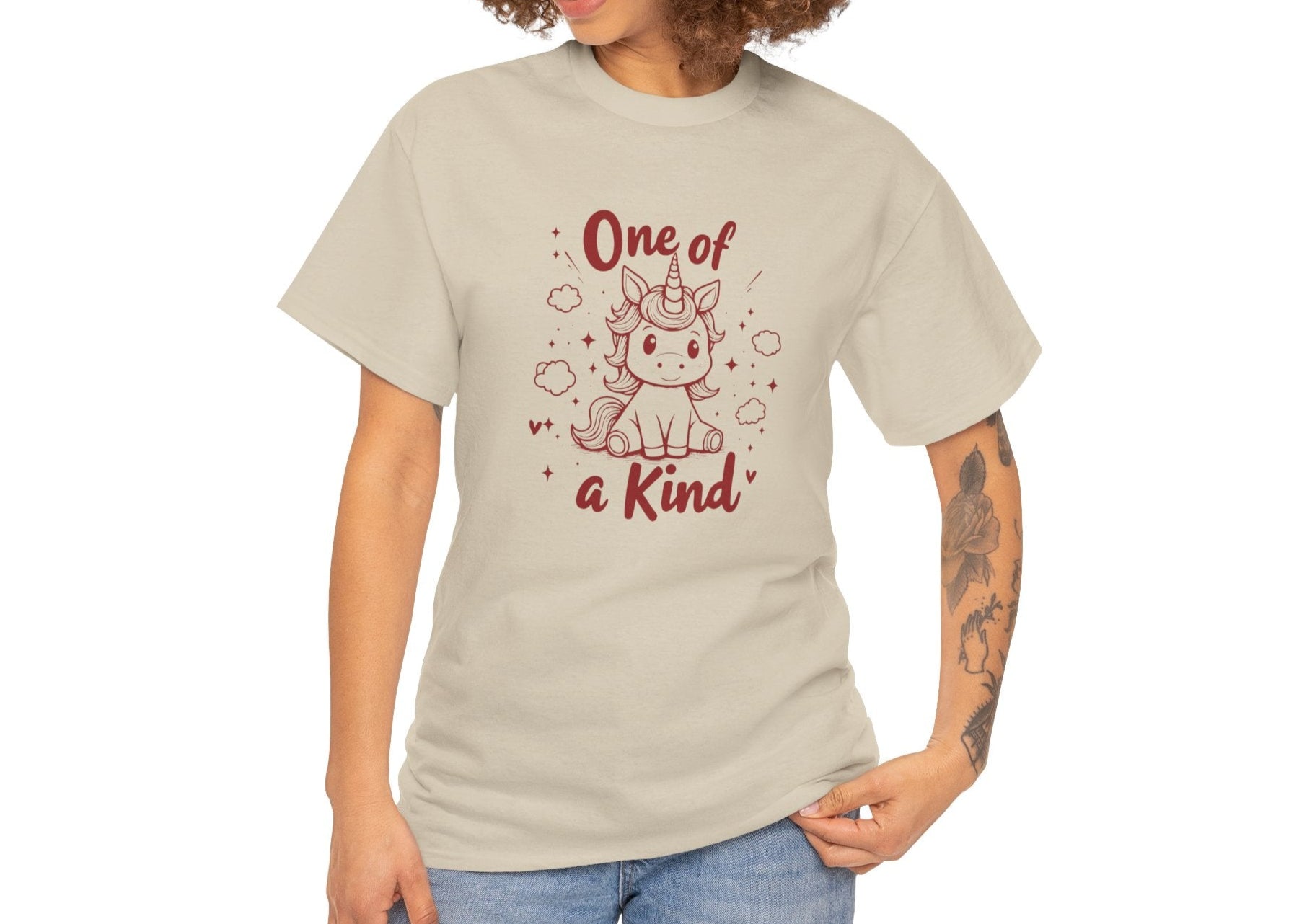 Modeled view of a beige T-shirt with "One of a Kind" text and a doodle-style unicorn surrounded by hearts and sparkles. Part of the Vivid Divergence Sensory Friendly Unisex Tees Range.