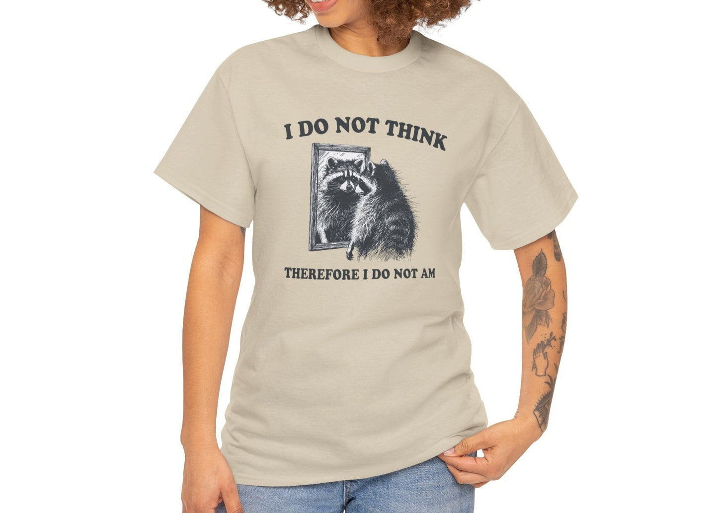 A beige T-shirt with a raccoon illustration and existential quote, modeled by a woman with curly hair. Part of the Vivid Divergence Sensory Friendly Unisex Tees Range.