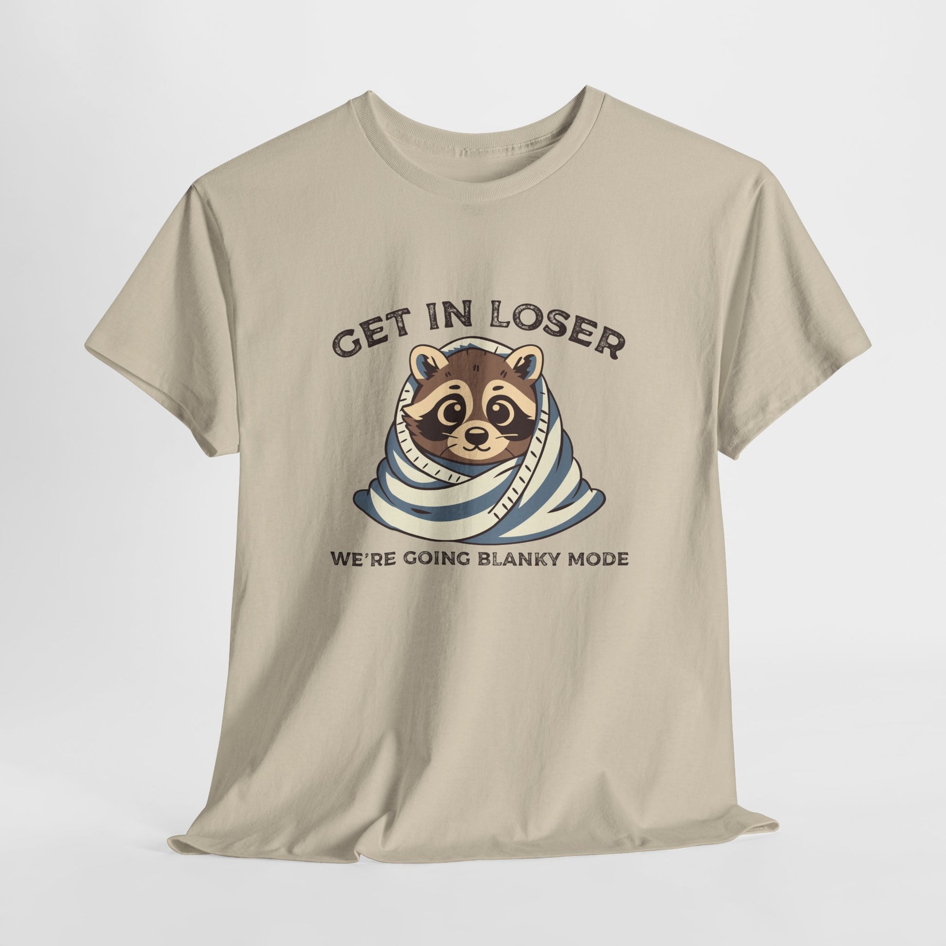 Hanging front view of a beige T-shirt featuring a cute raccoon wrapped in a blanket with text that reads "Get In Loser, We're Going Blanky Mode." Part of the Vivid Divergence Sensory Friendly Unisex Tees Range.