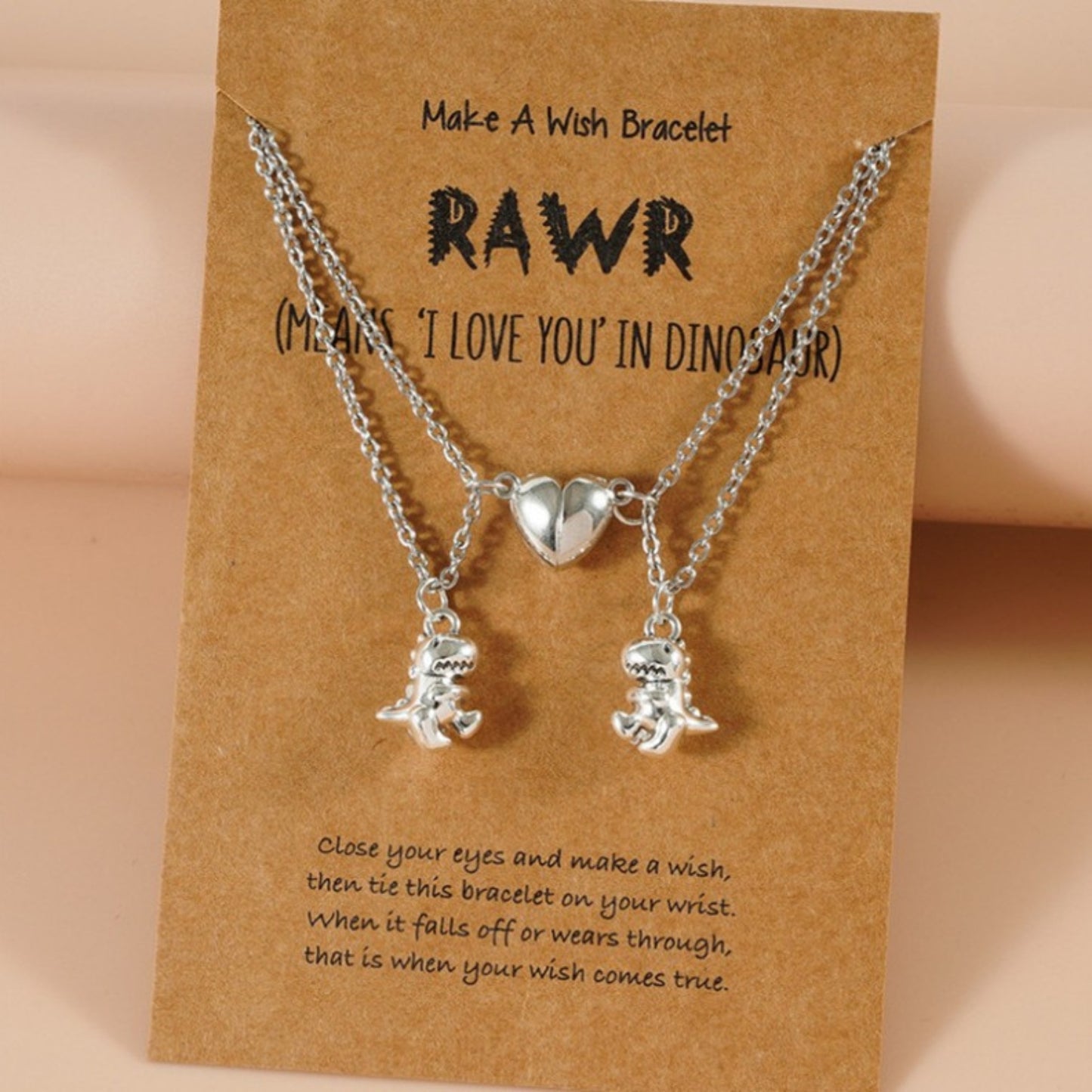 Silver best friend necklaces with magnetic heart and dinosaur pendants displayed on a “Make A Wish” gift card.