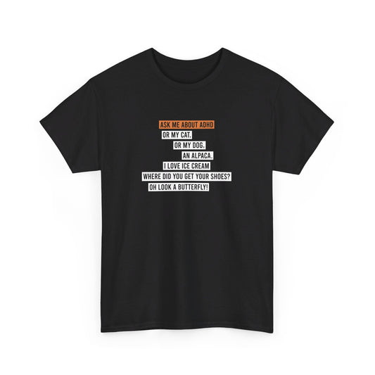 Front view of a black T-shirt featuring the text "Ask me about my ADHD, or my cat, or my dog, an alpaca, I love ice cream, Where did you get your shoes, oh look a butterfly" in white and orange. Part of the Vivid Divergence Sensory Friendly Unisex Tees Range.