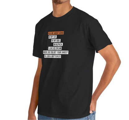 Side view of a black T-shirt worn by a model, showcasing the text "Ask me about my ADHD, or my cat, or my dog, an alpaca, I love ice cream, Where did you get your shoes, oh look a butterfly" in white and orange. Part of the Vivid Divergence Sensory Friendly Unisex Tees Range. 