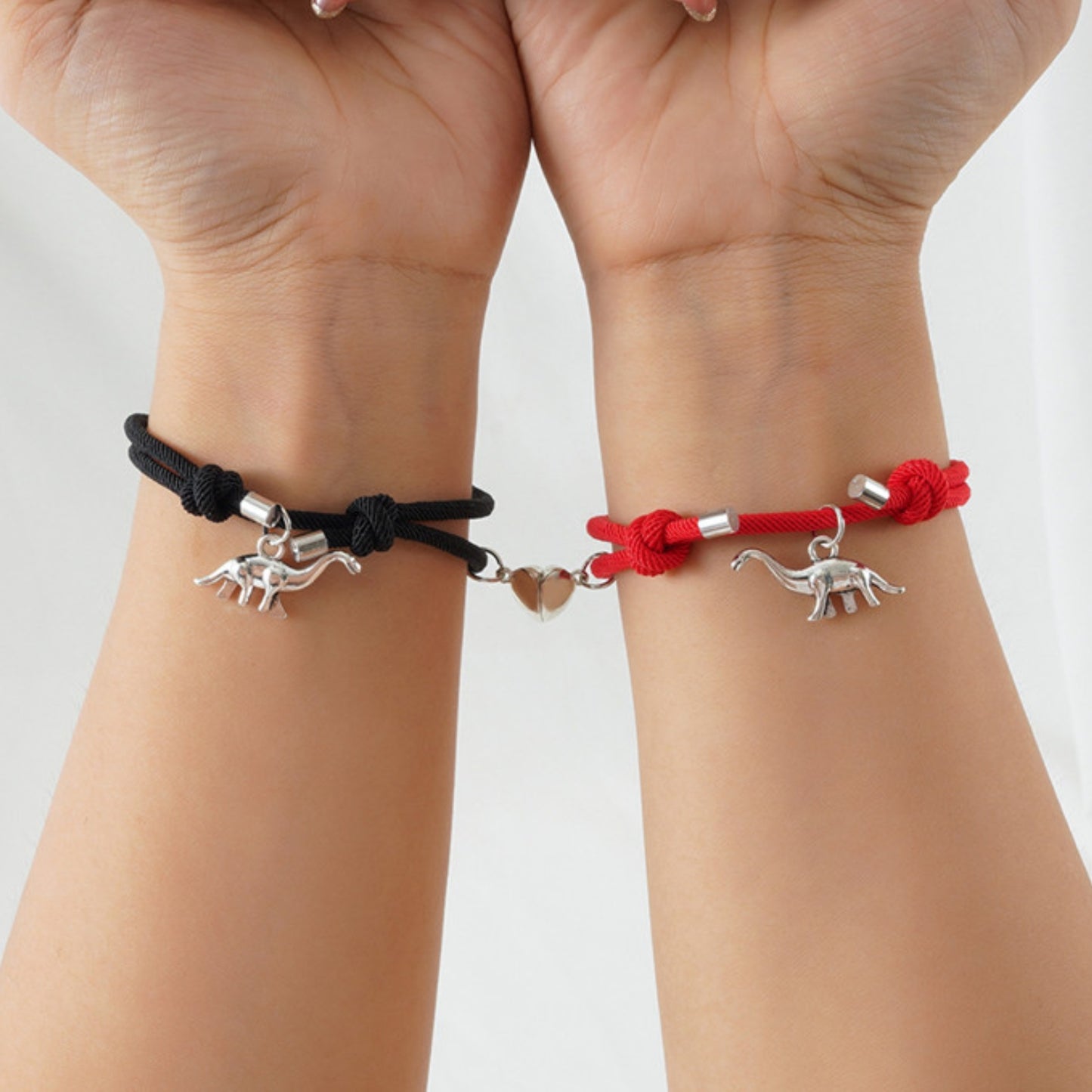 Black and red matching bracelets featuring silver Brontosaurus charms and a magnetic heart connector. A thoughtful gift for dino lovers.