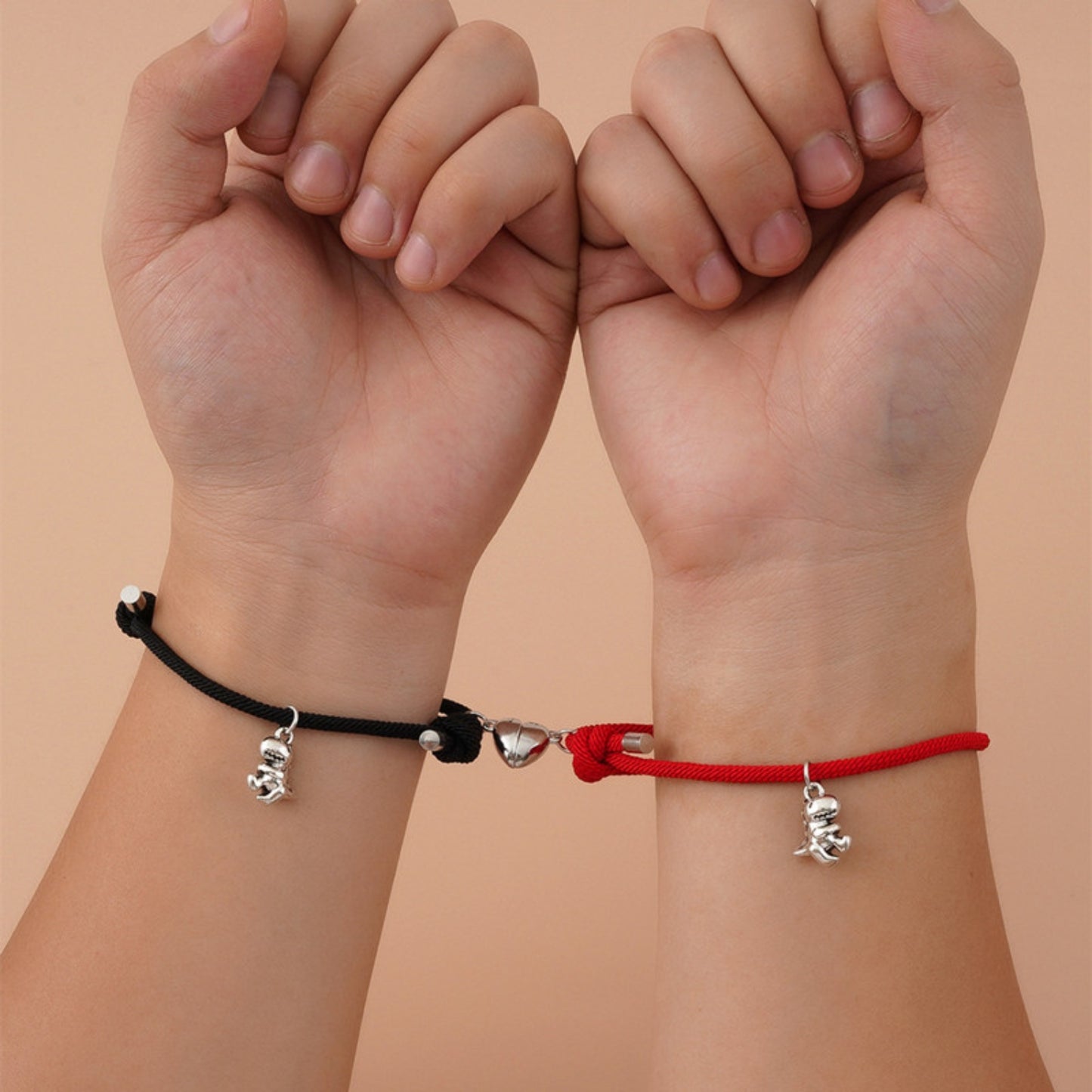 Black and red matching adjustable bracelets with silver dinosaur charms and magnetic heart accents. Ideal for couples or friends.