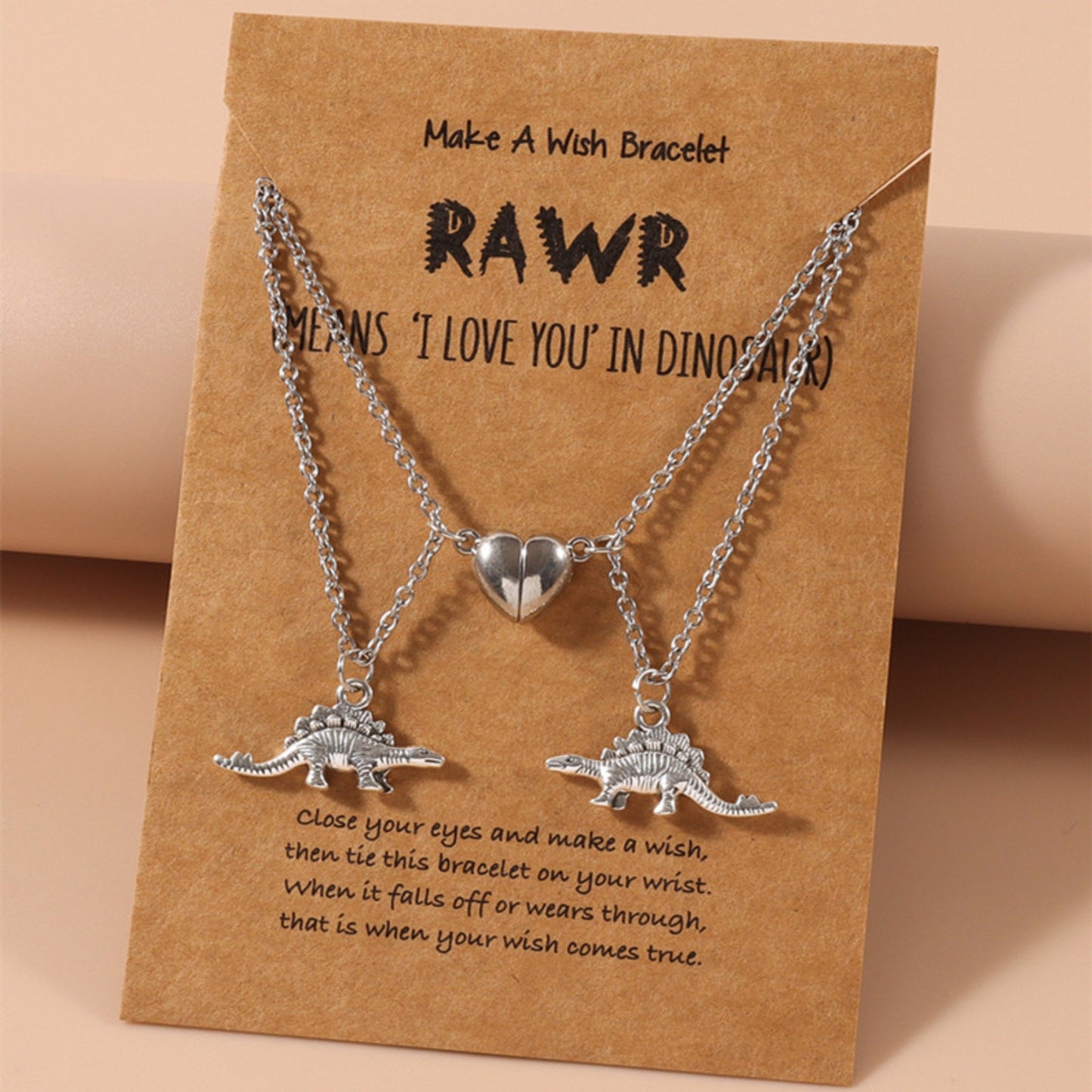 Magnetic couples necklace set featuring silver dinosaur pendants and heart charm on a “Make A Wish” card. Perfect gift.