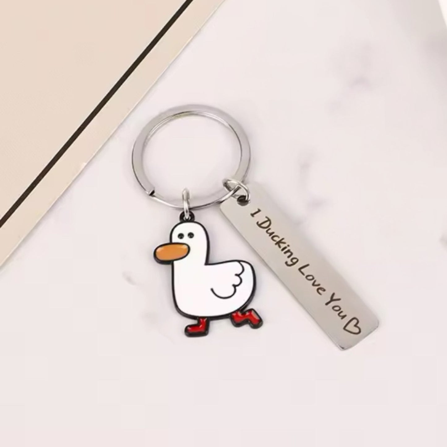 Duck keychain with a white duck charm wearing red boots and a silver "I Ducking Love You ♥" tag, displayed on a white marble background.