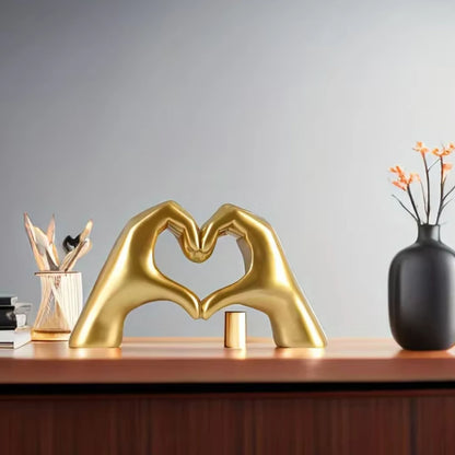 Gold hand-shaped sculpture forming a heart on a modern desk with minimalist decor. Unique dopamine decor and a lovely Valentine's Day gift.