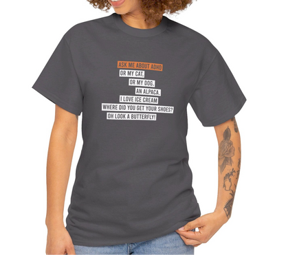 Side view of a gray T-shirt worn by a model, showcasing the text "Ask me about my ADHD, or my cat, or my dog, an alpaca, I love ice cream, Where did you get your shoes, oh look a butterfly" in white and orange. Part of the Vivid Divergence Sensory Friendly Unisex Tees Range.