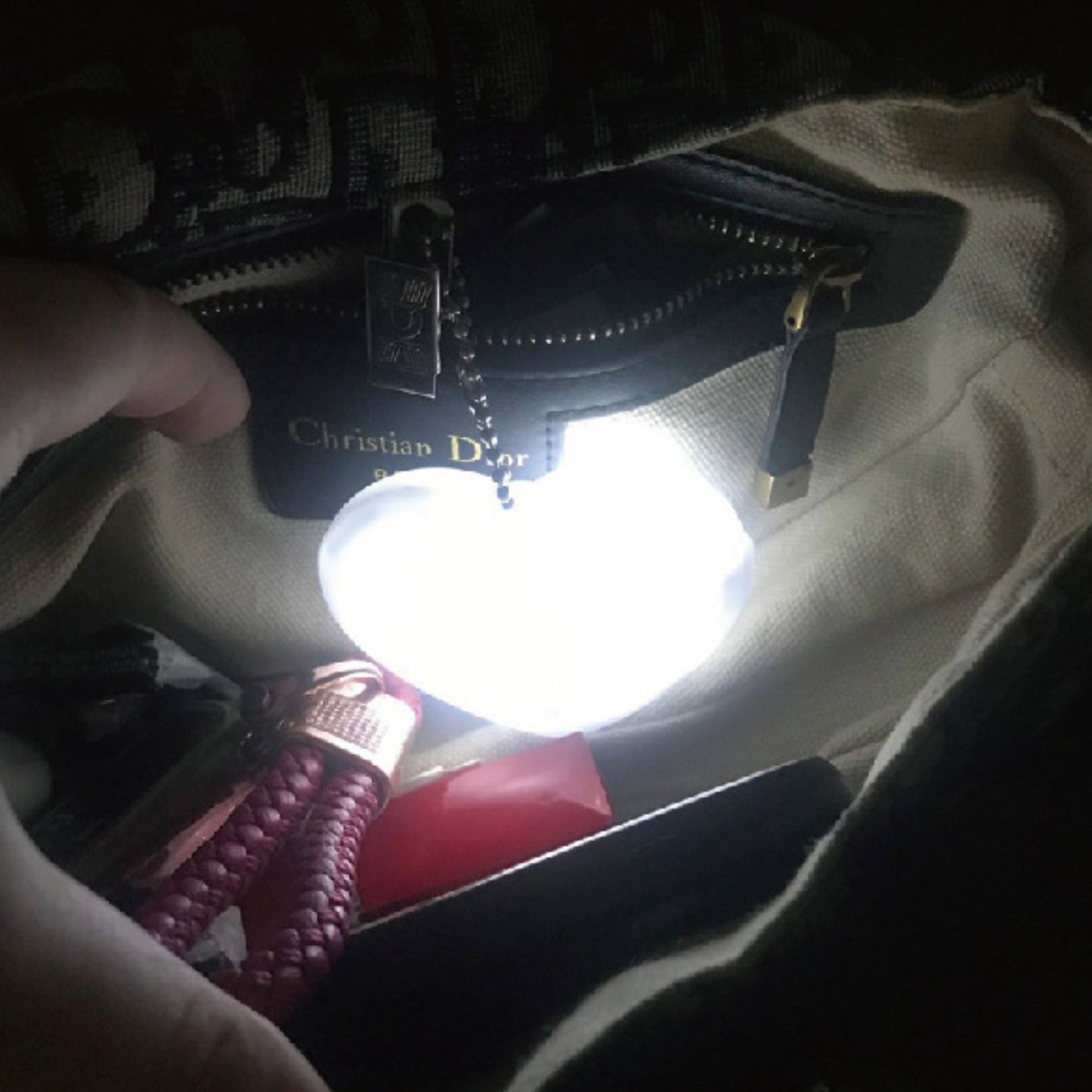 Heart-shaped LED bag clip illuminating the interior of a handbag, ideal for finding essentials in low light.