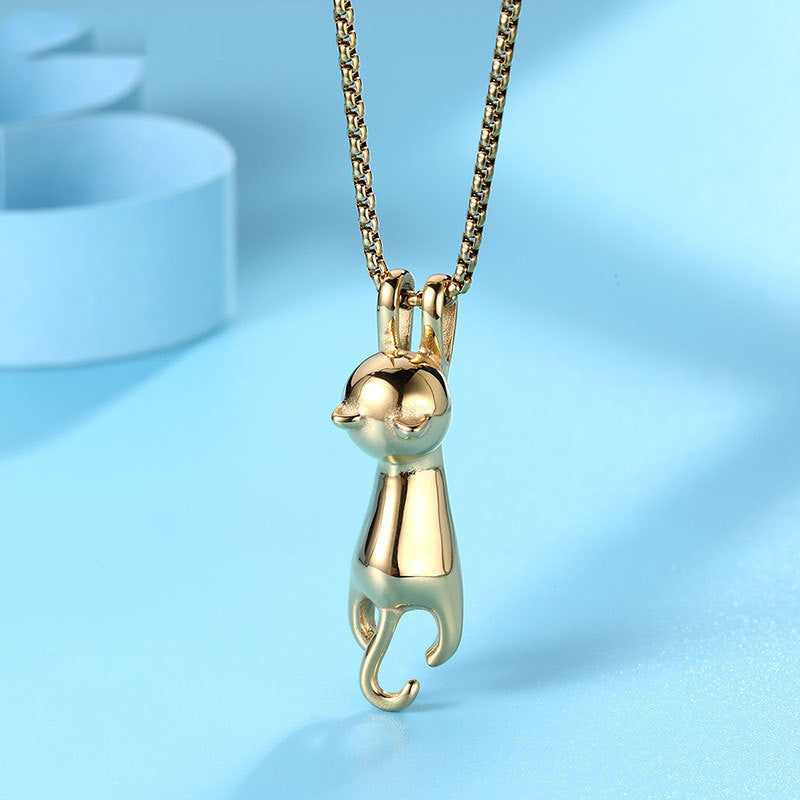 Close-up of the Hang Tight Cat Necklace in gold titanium steel, featuring a polished finish and a charming design of a cat dangling from the chain, displayed on a light blue background.