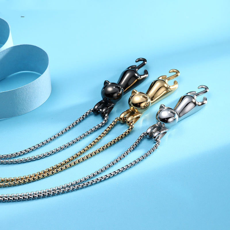 Three Hang Tight Cat Necklaces in titanium steel with silver, gold, black, each showcasing a playful cat hanging from the chain, set against a light blue background.