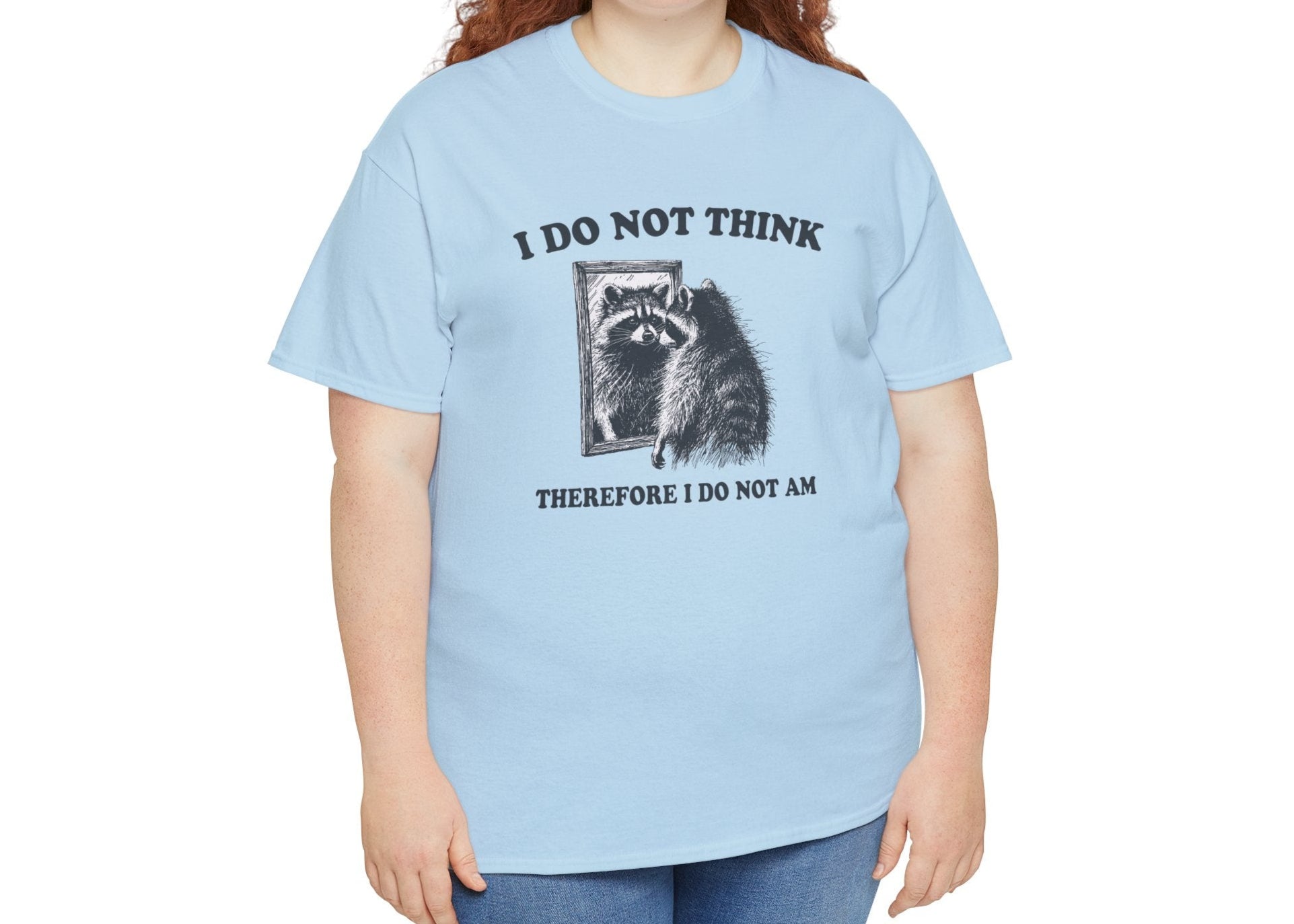 A light blue T-shirt with a raccoon illustration and existential quote, modeled by a woman. Part of the Vivid Divergence Sensory Friendly Unisex Tees Range.