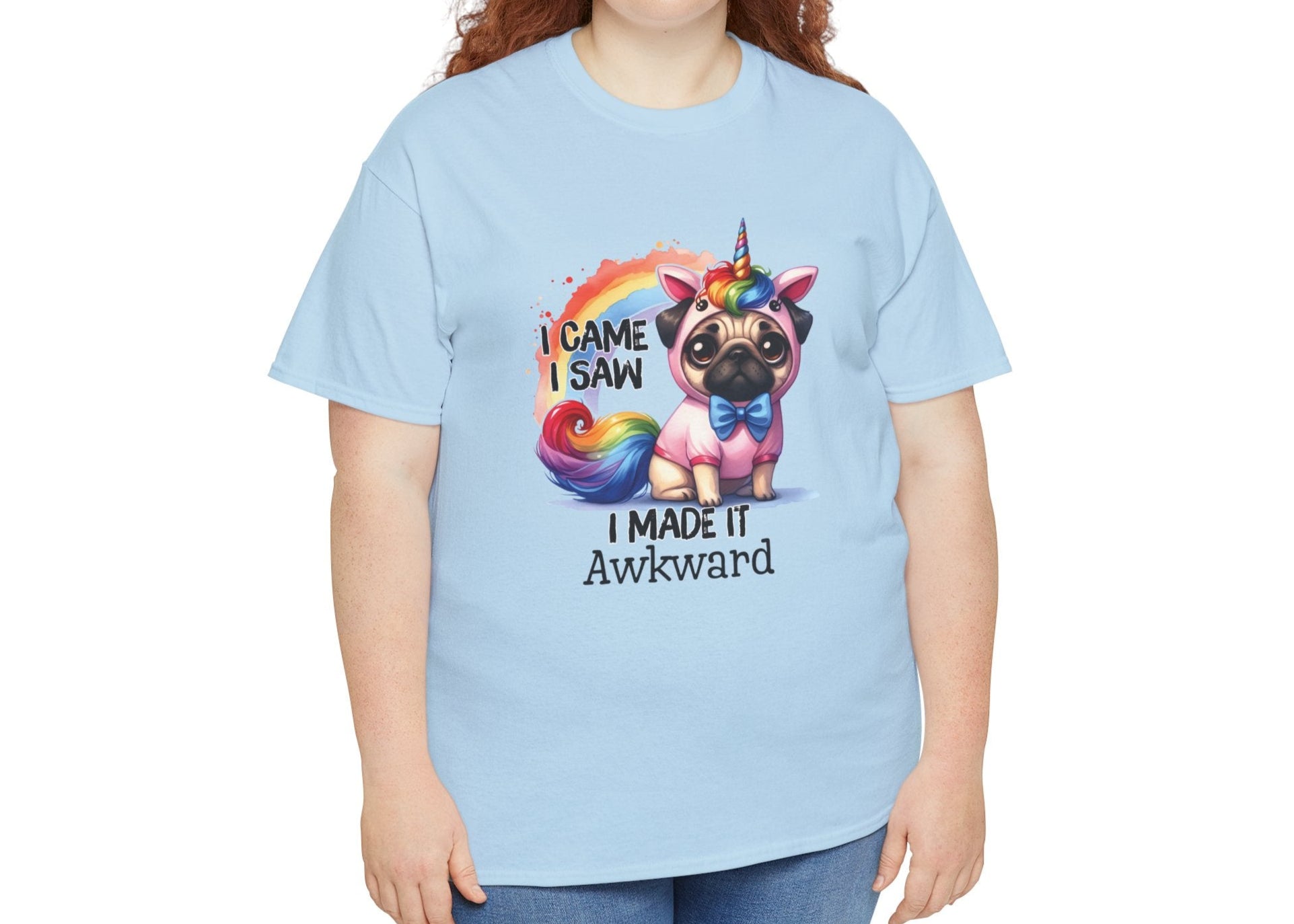 Plus-size woman wearing a light blue T-shirt featuring a colorful unicorn pug design with the text "I Came, I Saw, I Made It Awkward." Part of the Vivid Divergence Sensory Friendly Unisex Tees Range.