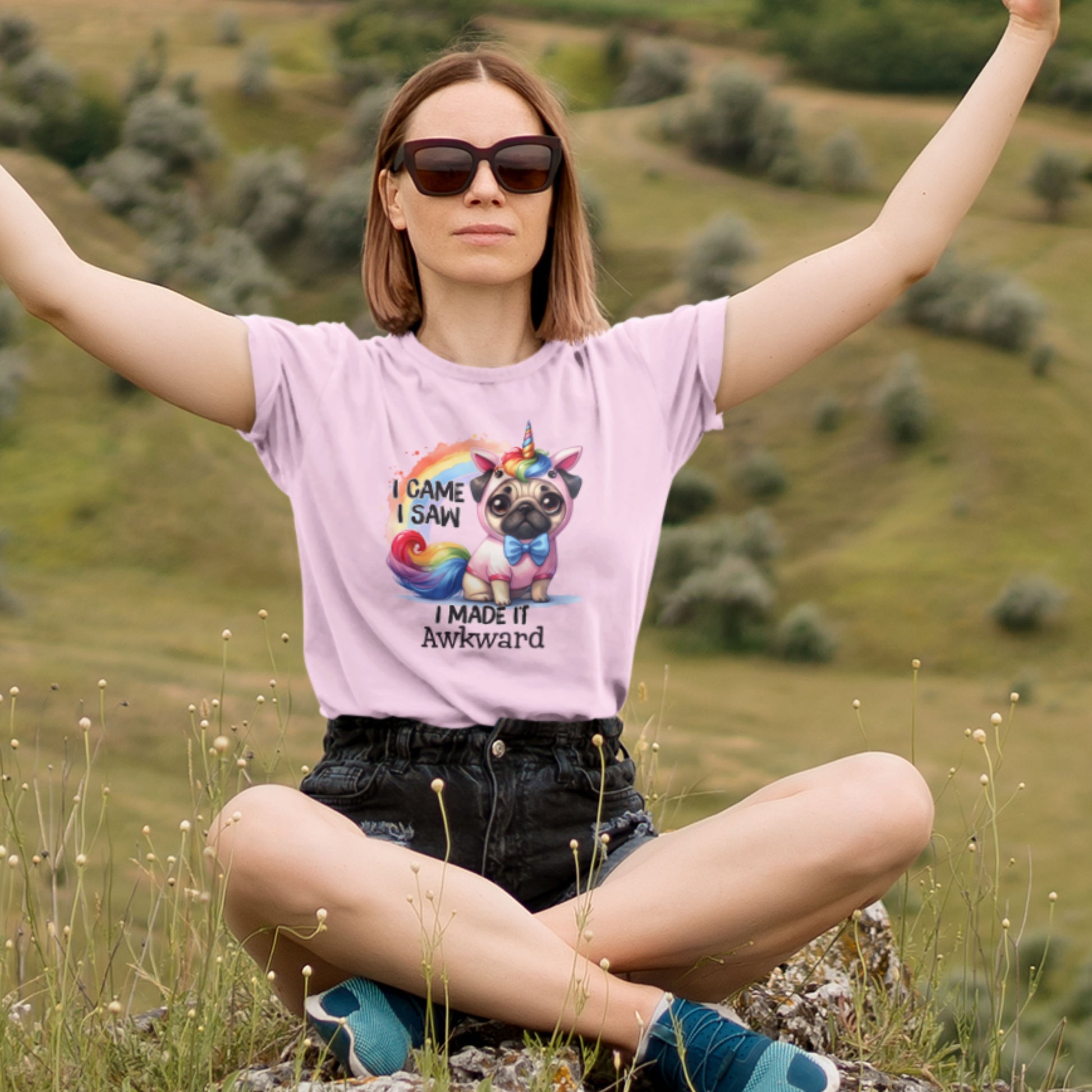 Modeled view of a light pink T-shirt featuring a pug dressed as a unicorn with the text "I Came, I Saw, I Made It Awkward." Part of the Vivid Divergence Sensory Friendly Unisex Tees Range.