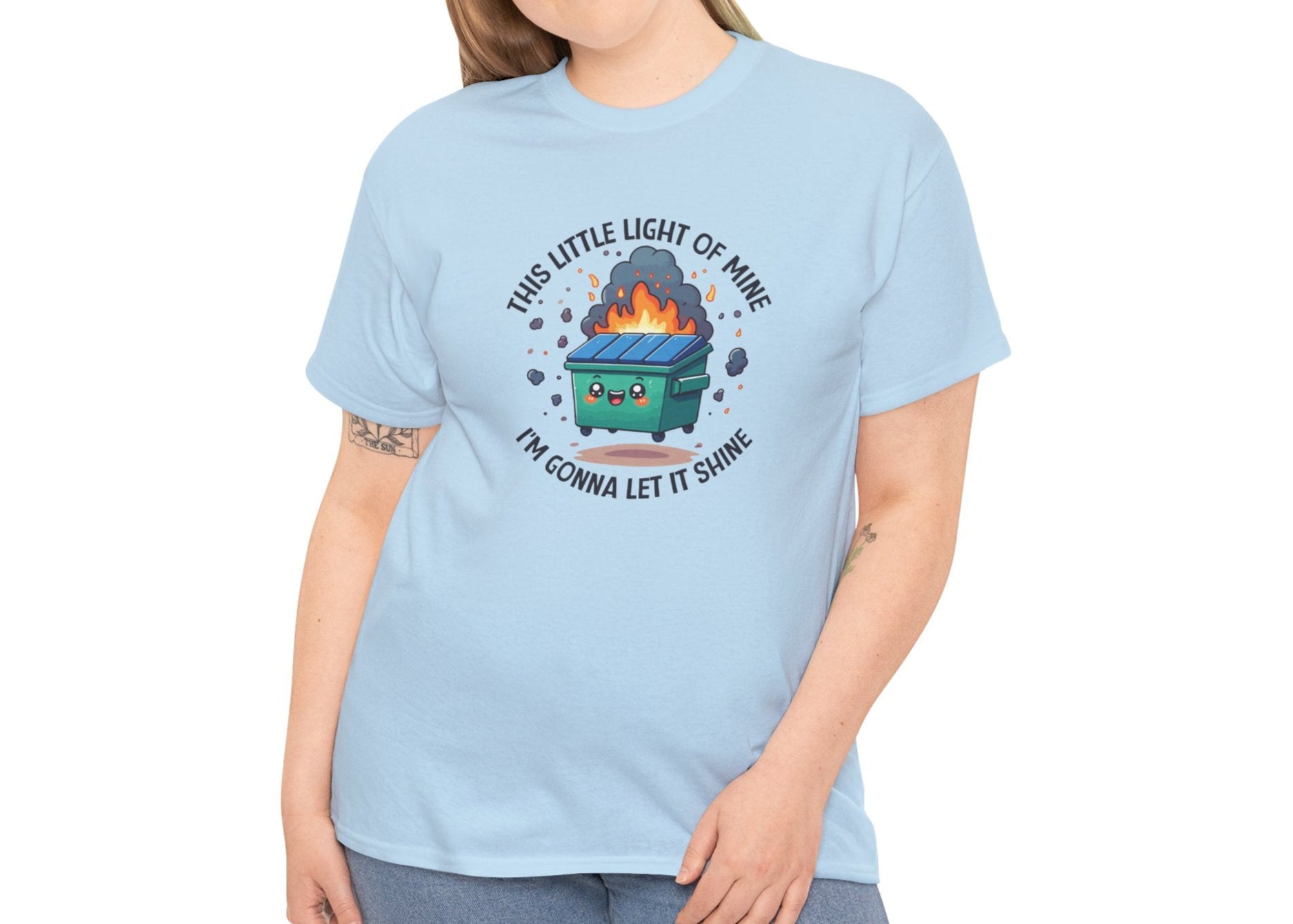 Person wearing a light blue T-shirt featuring a colorful dumpster fire graphic with the text "This Little Light Of Mine I'm Going To Let It Shine." Part of the Vivid Divergence Sensory Friendly Unisex Tees Range.