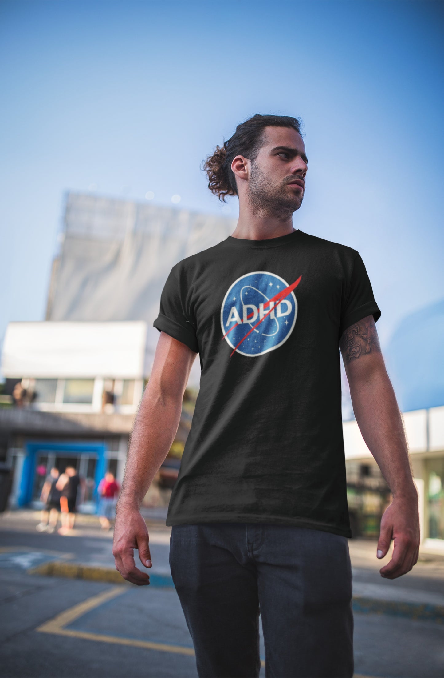 Man outdoors wearing a black ADHD NASA parody T-shirt with a space-themed logo. Part of the Vivid Divergence Sensory Friendly Unisex Tees Range.