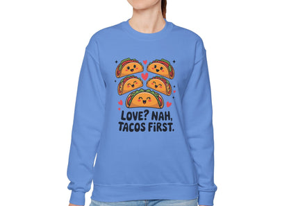 Model wearing a blue sweatshirt with "Love? Nah. Tacos First." text and cute taco characters design in orange and brown. Exclusive release for Valentine's Day. Part of the Vivid Divergence Sensory Friendly Sweaters Range.