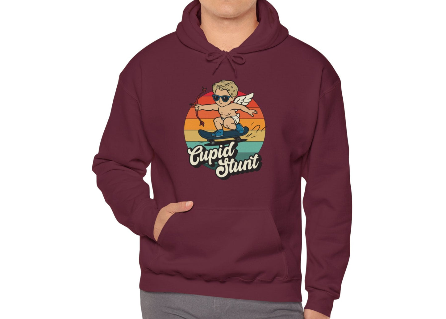 Model wearing a maroon hoodie with a vintage sunset design featuring Cupid riding a skateboard and "Cupid Stunt" text. Exclusive release for Valentine's Day. Part of the Vivid Divergence Sensory Friendly Sweaters Range.