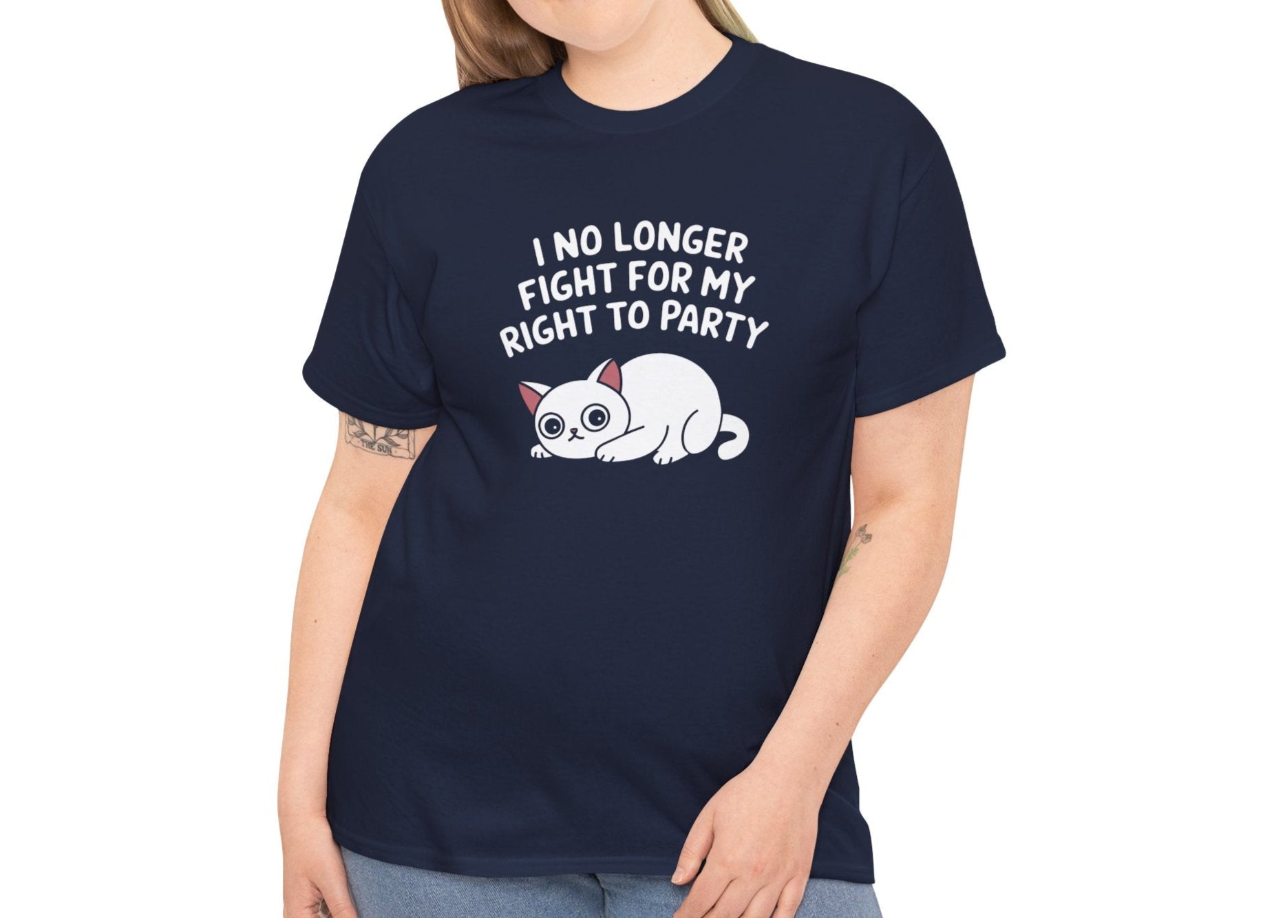 Model wearing a navy blue T-shirt with the text "I No Longer Fight For My Right To Party" above a napping white cat graphic, smiling casually. Part of the Vivid Divergence Sensory Friendly Unisex Tees Range.