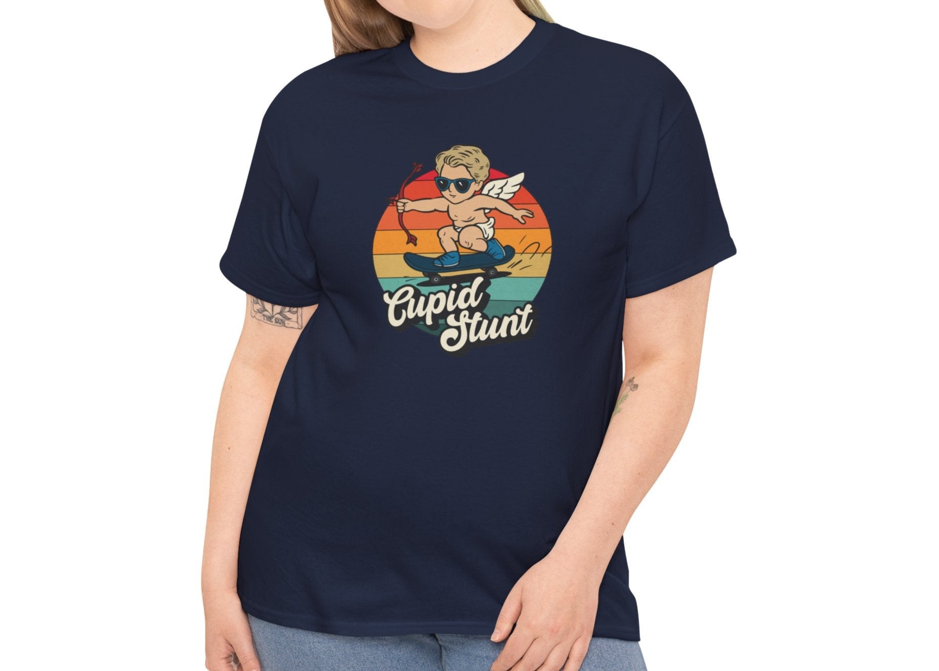 Woman wearing a navy T-shirt featuring a retro sunset background and a cartoon cupid with the text "Cupid Stunt." Exclusive release for Valentine’s Day. Part of the Vivid Divergence Sensory Friendly Unisex Tees Range.