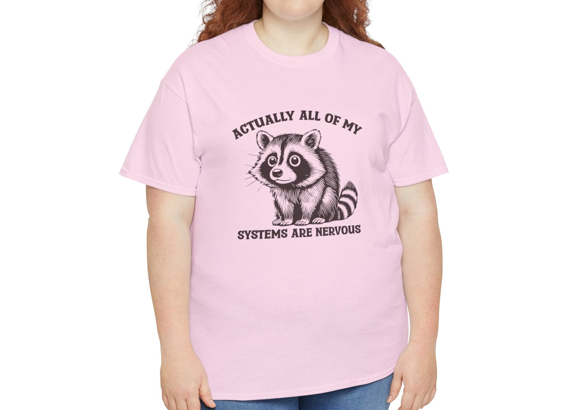 Model wearing a pink T-shirt with "Actually All Of My Systems Are Nervous" text and a raccoon graphic. Part of the Vivid Divergence Sensory Friendly Unisex Tees Range.
