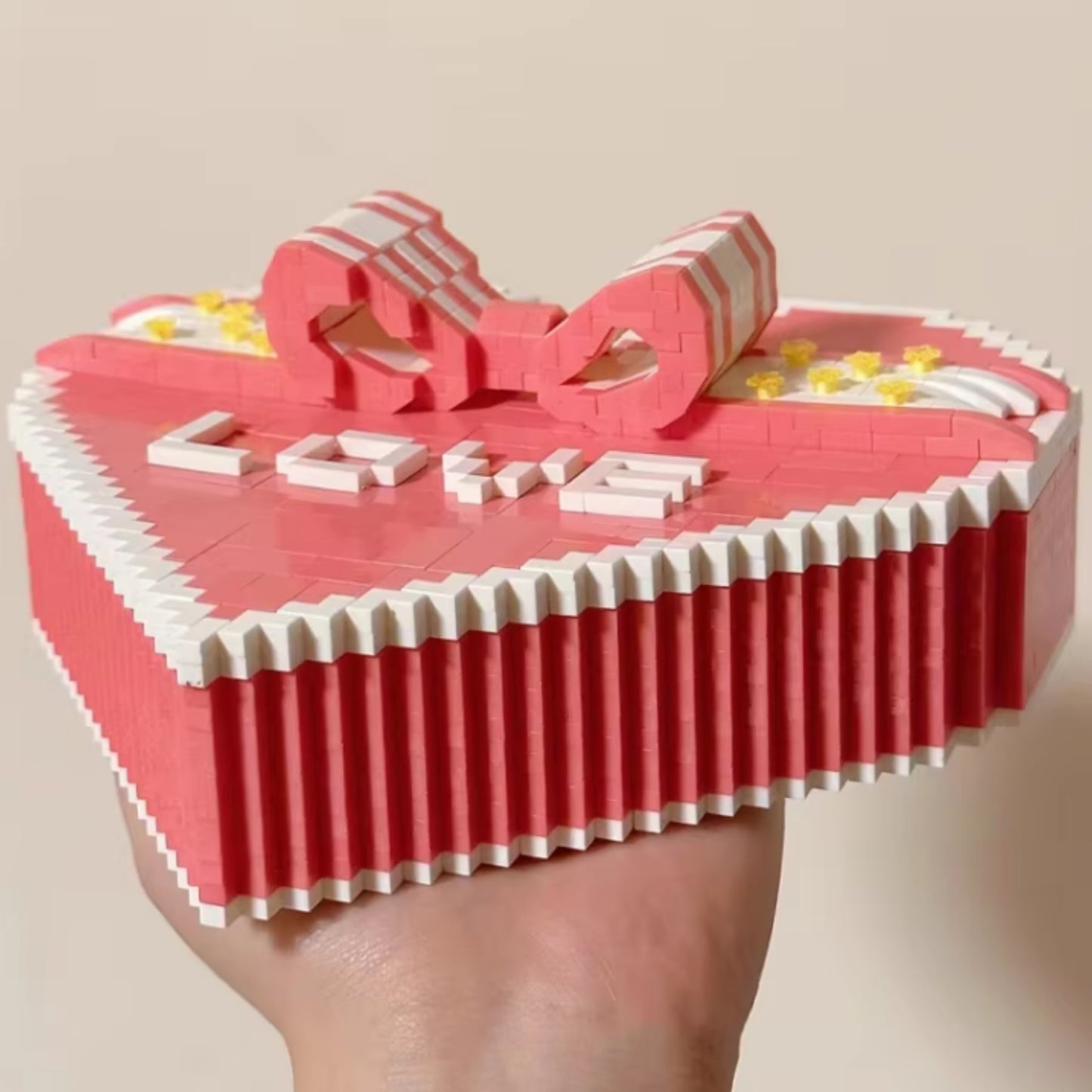 Close-up of a pink heart-shaped building block box with the word "LOVE" and a bow design on the lid.