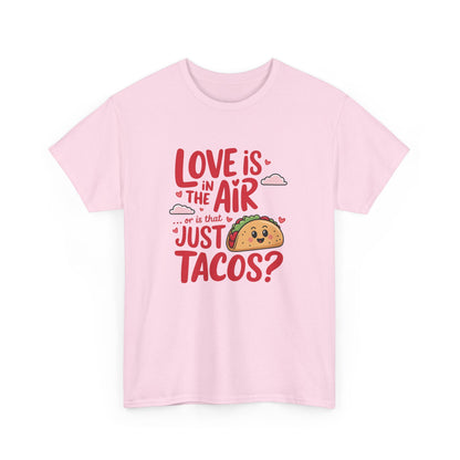 Front view of a pink T-shirt featuring red and black text with a taco illustration that reads "Love Is In The Air Or Is It Just Tacos?" Exclusive release for Valentine’s Day. Part of the Vivid Divergence Sensory Friendly Unisex Tees Range.