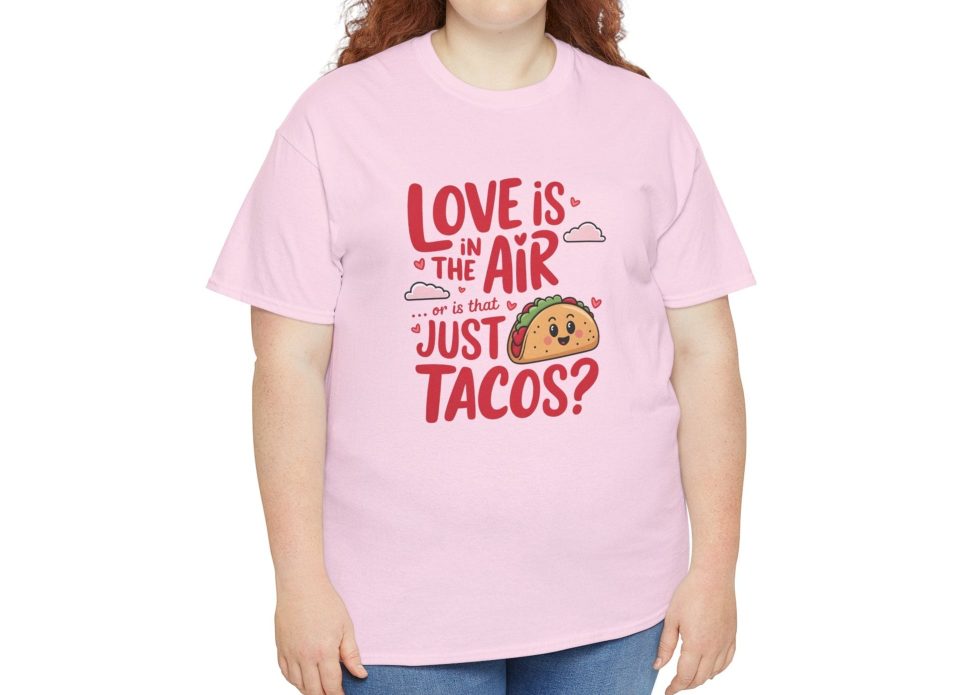 Woman wearing a pink T-shirt featuring red and black text with a taco illustration that reads "Love Is In The Air Or Is It Just Tacos?" Exclusive release for Valentine’s Day. Part of the Vivid Divergence Sensory Friendly Unisex Tees Range.