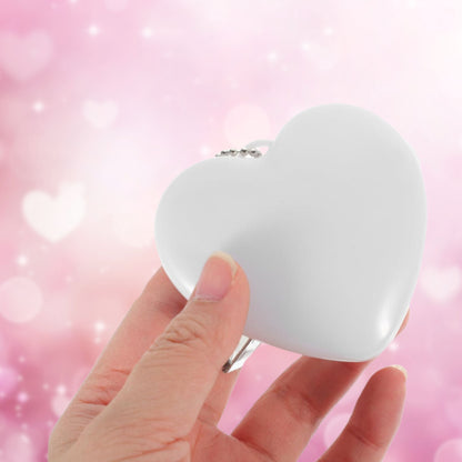 Heart-shaped LED bag clip held in hand, showcasing its lightweight and compact design for portability.