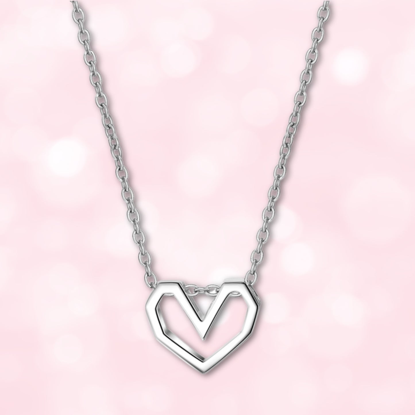 Front view of a silver geometric open heart necklace on a soft pink background, highlighting its minimalist and elegant design.