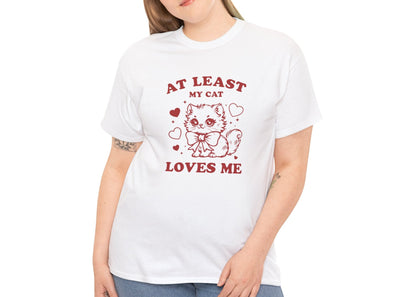 Woman wearing a white T-shirt with red text and cat illustration that reads "At Least My Cat Loves Me." Exclusive release for Valentine’s Day. Part of the Vivid Divergence Sensory Friendly Unisex Tees Range.