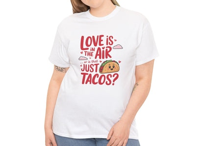 Woman wearing a white T-shirt featuring red and black text with a taco illustration that reads "Love Is In The Air Or Is It Just Tacos?" Exclusive release for Valentine’s Day. Part of the Vivid Divergence Sensory Friendly Unisex Tees Range.