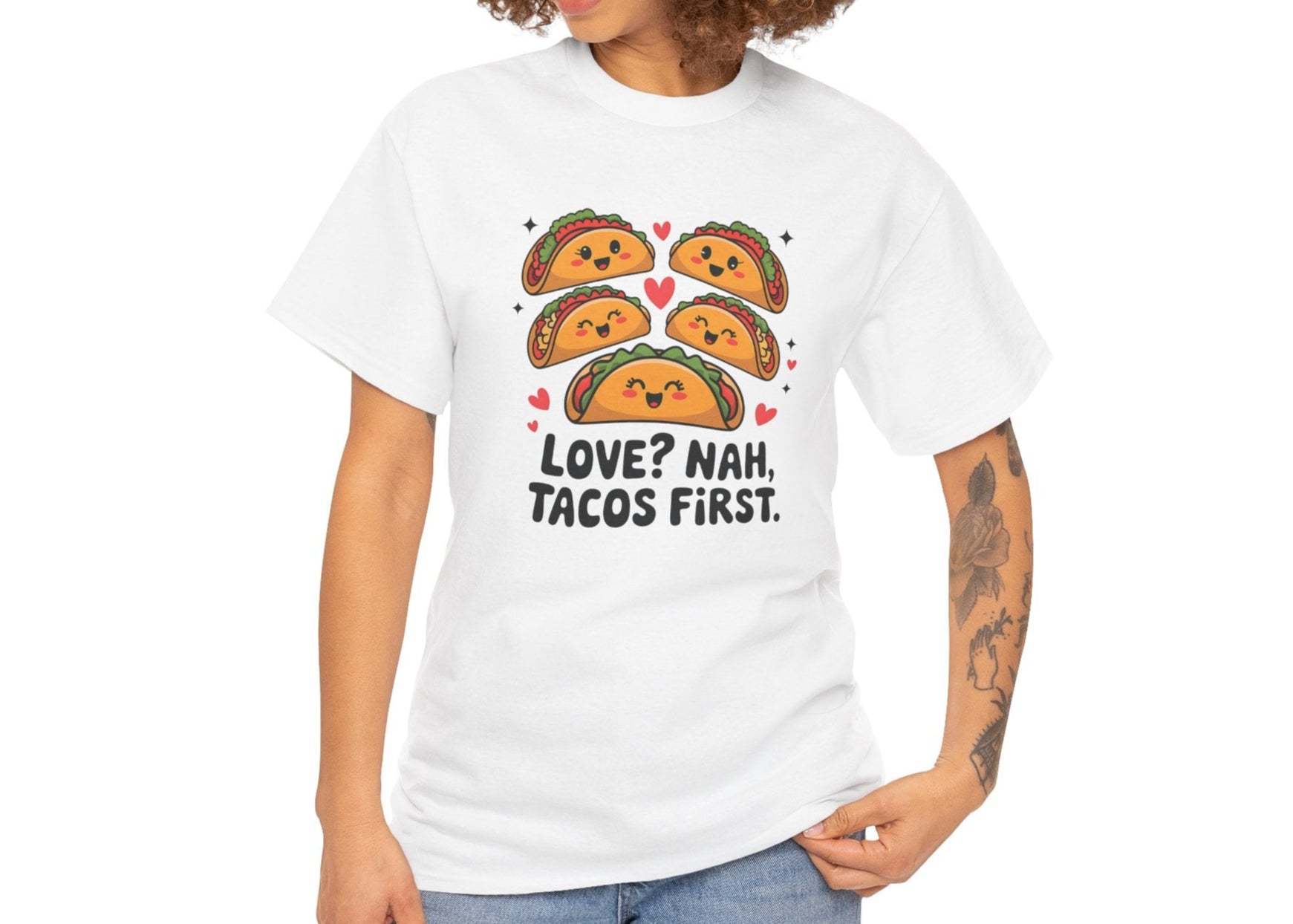 Front view of a white T-shirt worn by a woman with curly hair, featuring an illustration of tacos and black text that reads "Love? Nah, Tacos First." Exclusive release for Valentine’s Day. Part of the Vivid Divergence Sensory Friendly Unisex Tees Range.