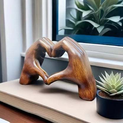 Wooden look hand-shaped sculpture forming a heart on a window ledge with plants. A beautiful piece of dopamine decor and a perfect gift for Valentine's Day.